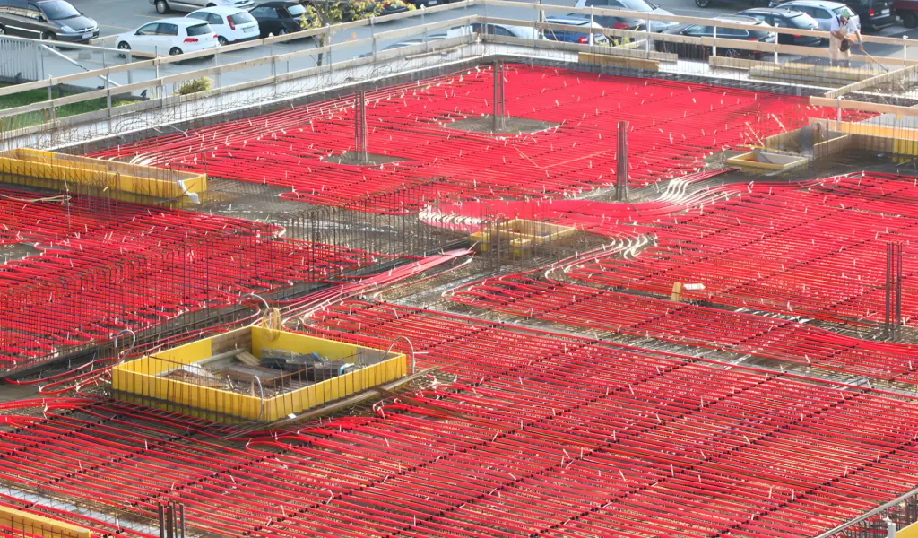 Wet concrete underfloor heating and cooling installation on an industrial construction site