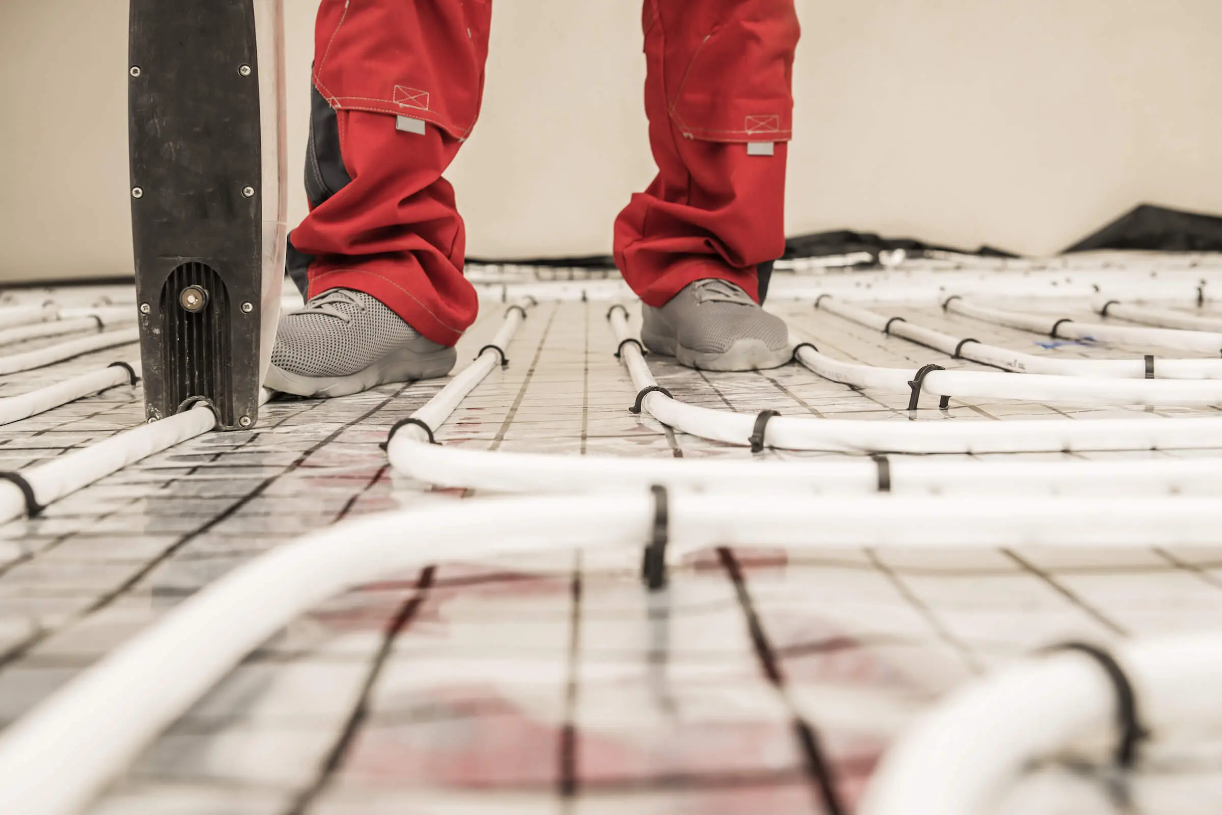 Fluxbite worker applying radiant underfloor heating pipe installation for offices