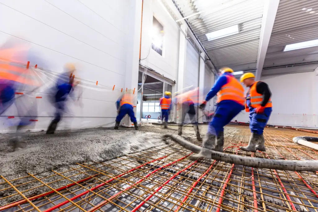 Workers do concrete screed after underfloor heating installation